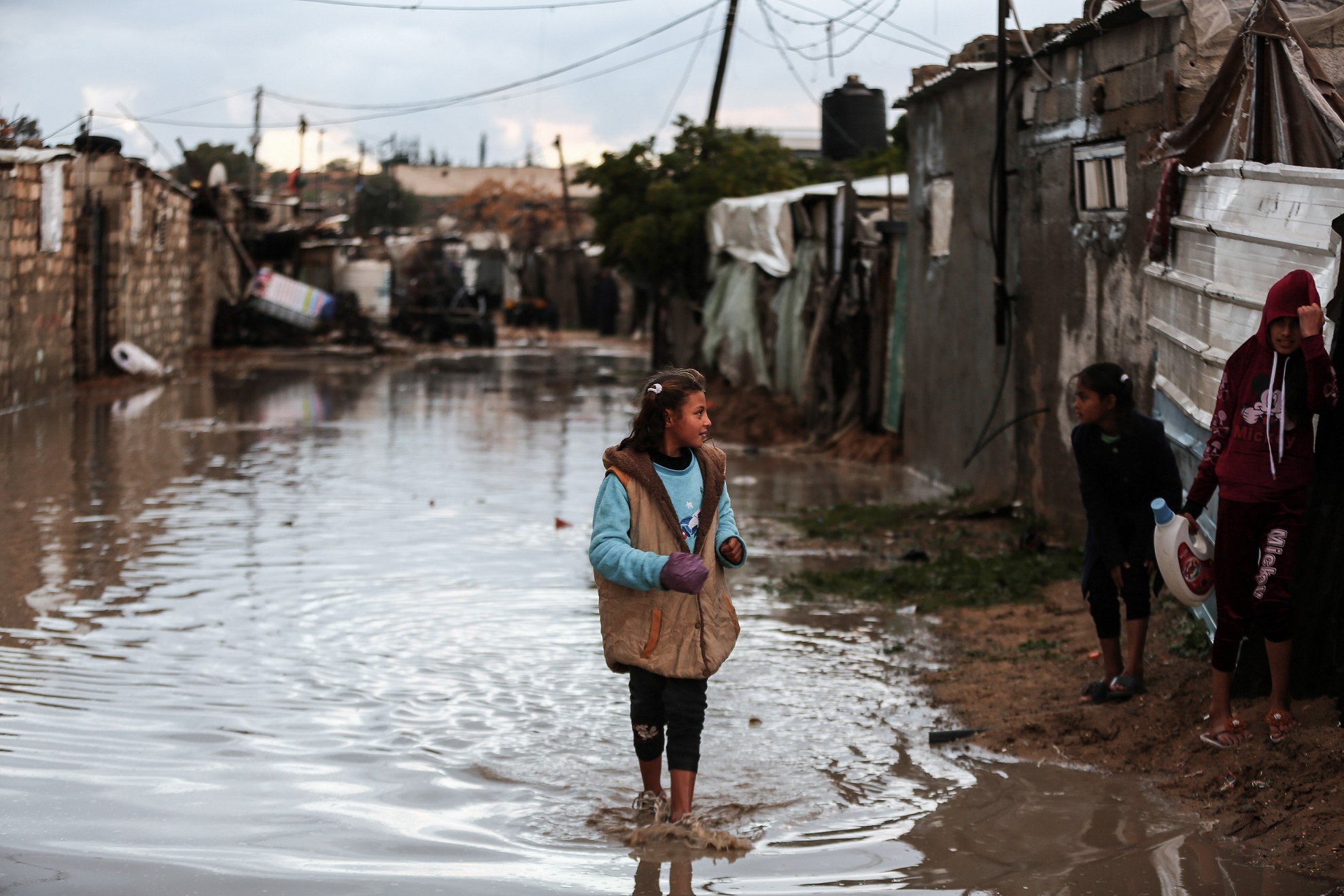 A child walks through a flooded street past damaged homes
